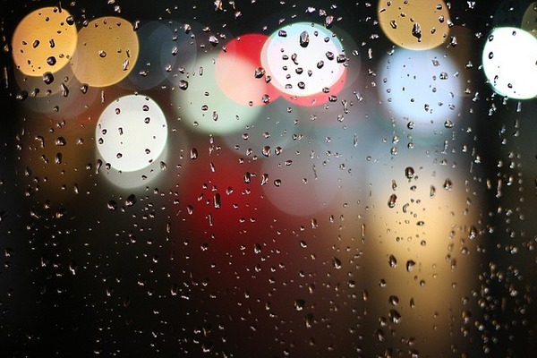 colored lights viewed through glass speckled with raindrops