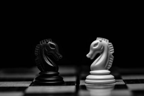 Image of two knights on a chessboard, facing each other as if in conflict