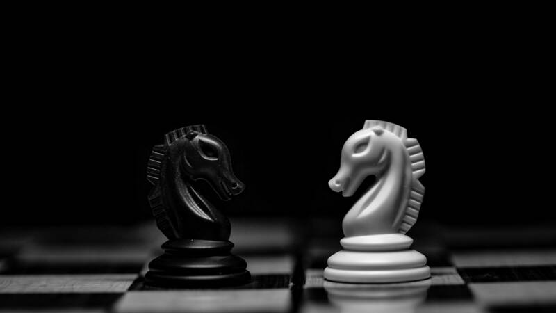 Image of two knights on a chessboard, facing each other as if in conflict