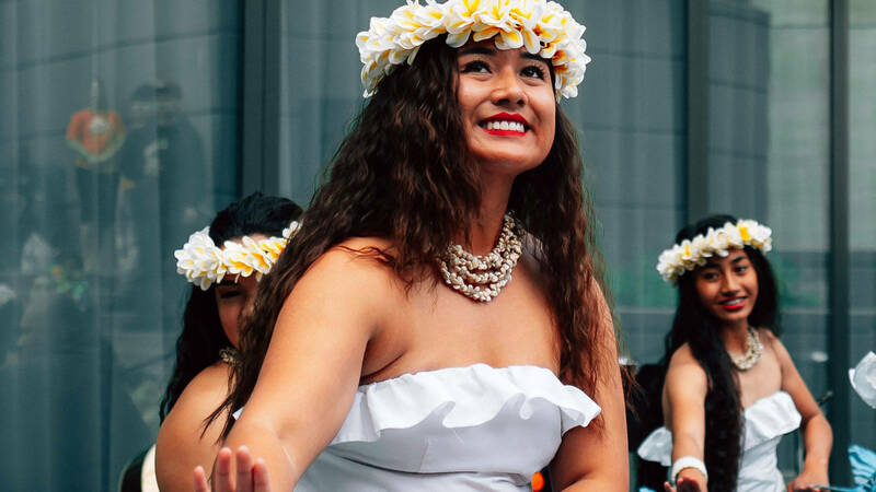 A young asian woman smiling in a white dress with a crown of flowers around her head.