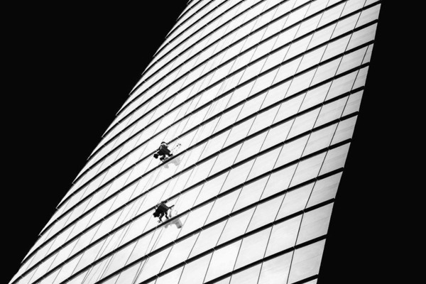 Window cleaners on a apparatus hanging off the side of a skyscraper in Ho Chi Minh City, Vietnam