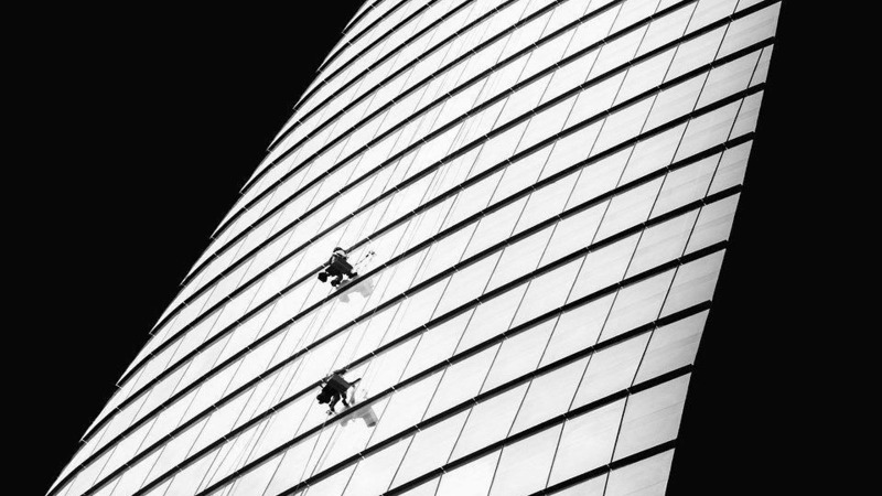 Window cleaners on a apparatus hanging off the side of a skyscraper in Ho Chi Minh City, Vietnam