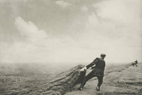 Farmer pulling sod over a dusty field in black and white