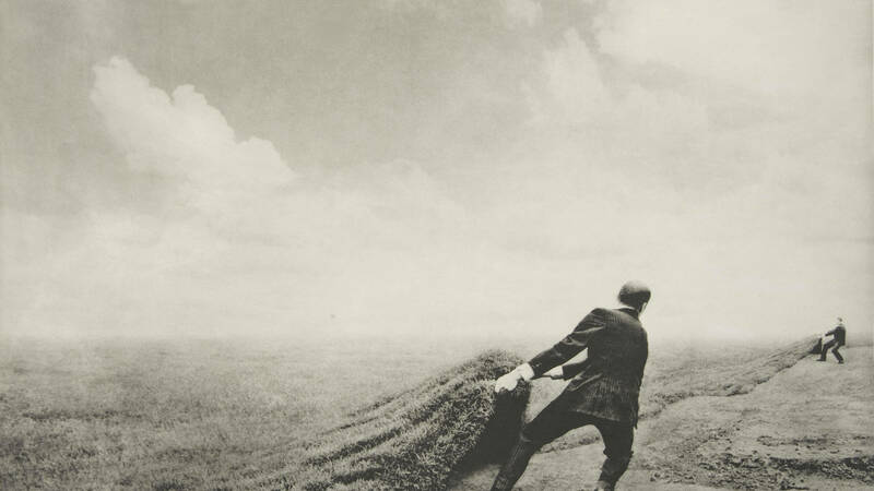 Farmer pulling sod over a dusty field in black and white