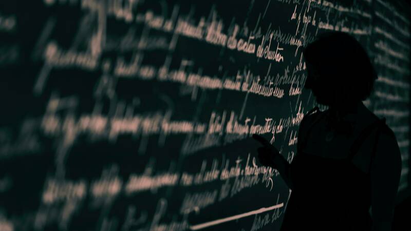 Image of figure in silouette at a blackboard doing work