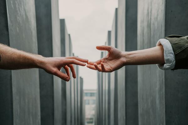 Two hands reaching out and touching each other against an industrial background.