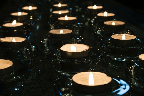 Rows of lit tea candles against a dark background