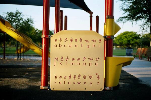 A yellow sign displays the ASL alphabet is part of a playground structure