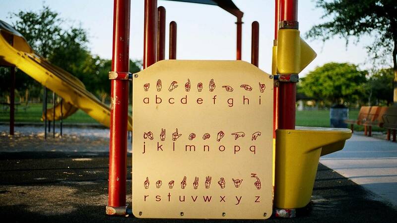A yellow sign displays the ASL alphabet is part of a playground structure