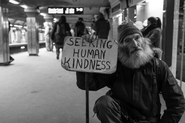 Homeless man with sign saying, "Seeking human kindess"