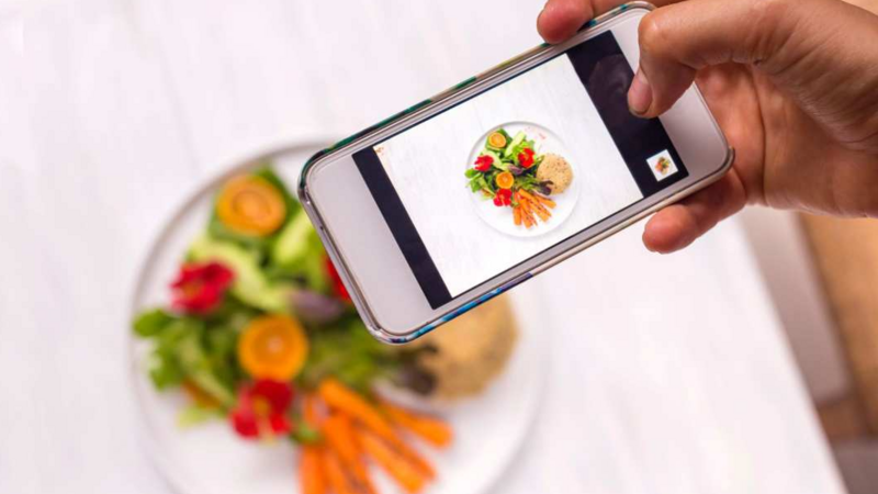 Person taking photo with smartphone of a plate of vegetables