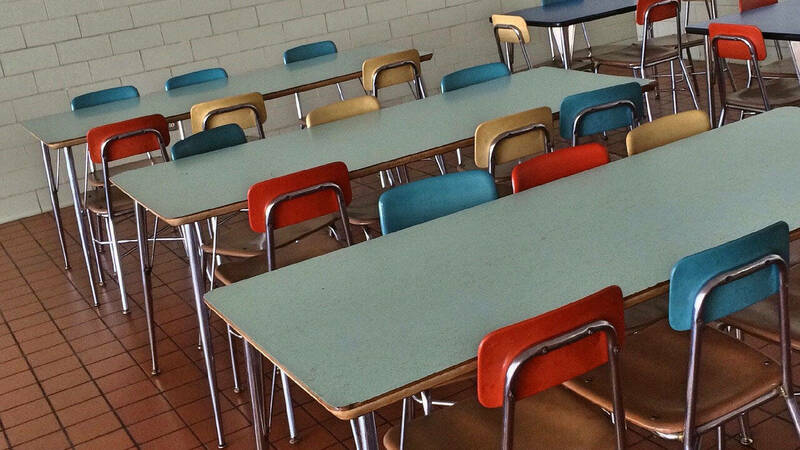 Image of empty school cafeteria seats and tables