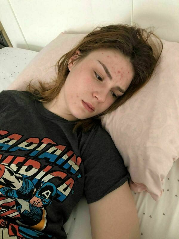 a young woman lying in bed wearing a Captain America t-shirt
