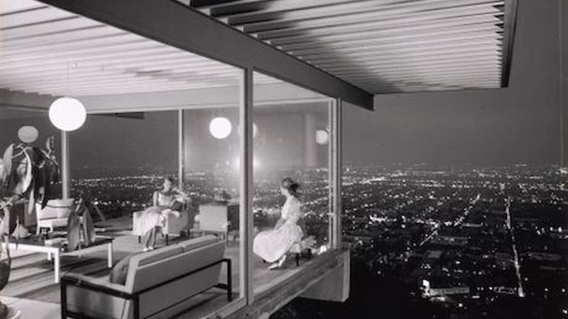a black and white photo of people sitting inside a house overlooking Los Angeles