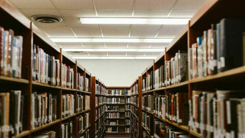 Two stacks of books in a library, on the left and the right, with lights overhead