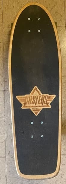 a black skateboard with the logo "Dusters"
