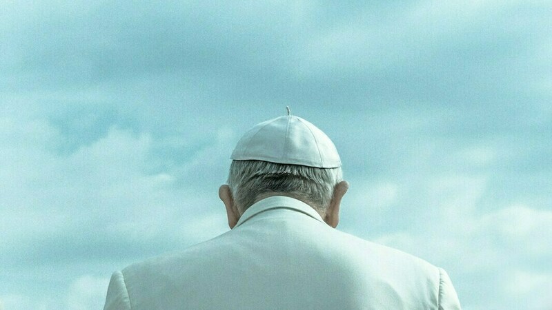 The Pope photographed from behind in front of a blue sky