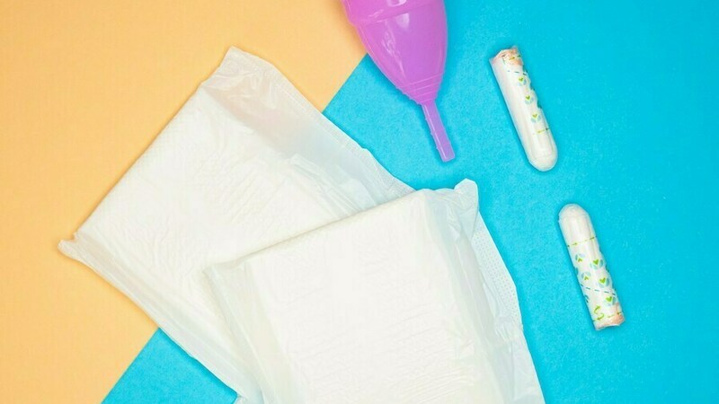 Pads, tampons, and menstrual cup shown on a yellow and blue background