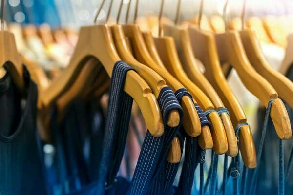Close up of wooden clothes hangers on a rack holding blue colored clothing